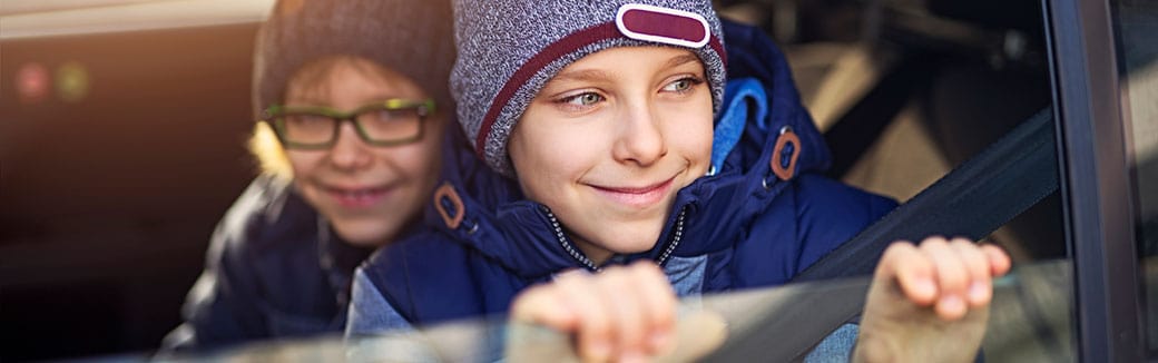 two elementary-school boys looking out a car window