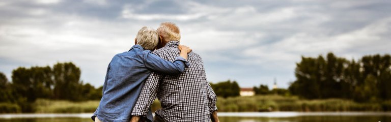 older couple outside with their back to us, arms around each other