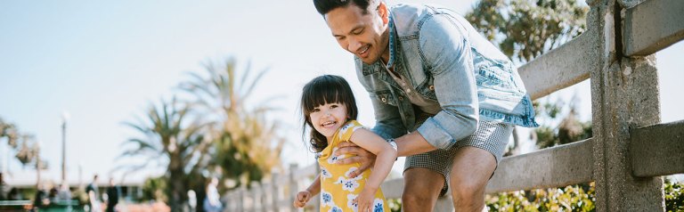 A father helps his daughter on a skateboard